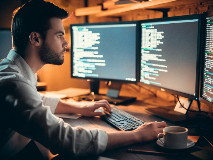 A man working from home and looking at his monitors