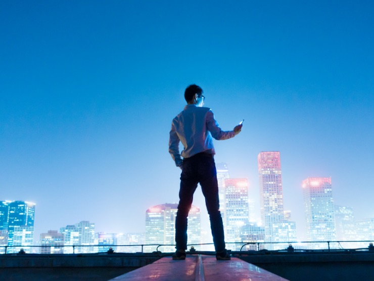 A man standing on a roof looking at city at night