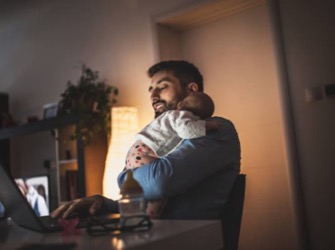 Man hold baby while typing on laptop