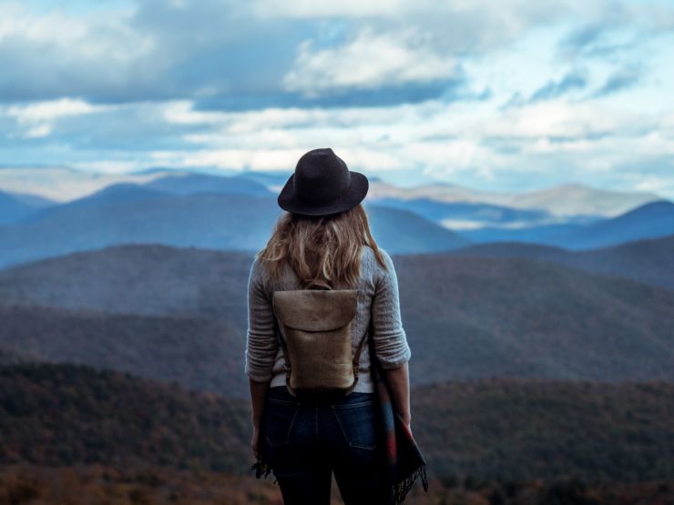 Woman wearing hat and backpack overlooking a valley