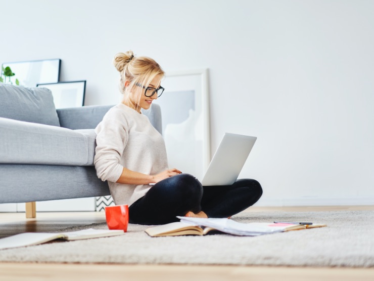 A person sitting on the floor and typing on their laptop
