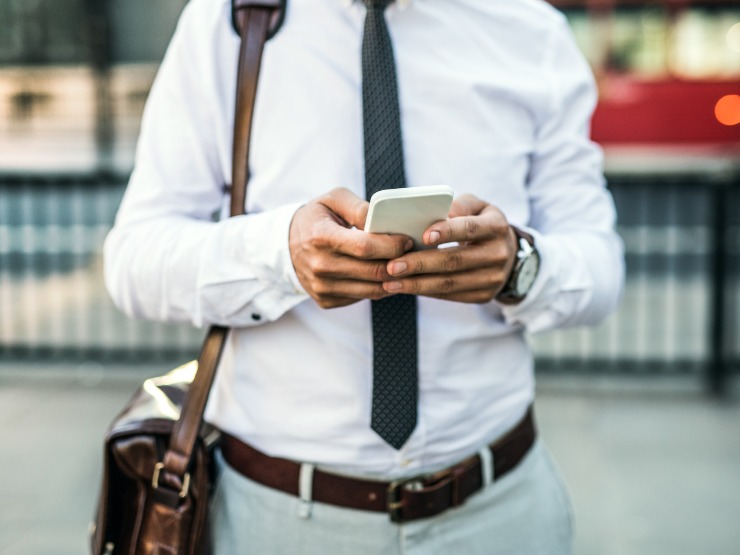 A photo of a man's torso and hands as he uses a phone