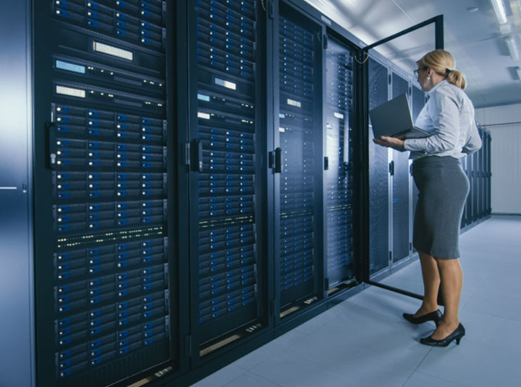 A woman holding a laptop in a server room