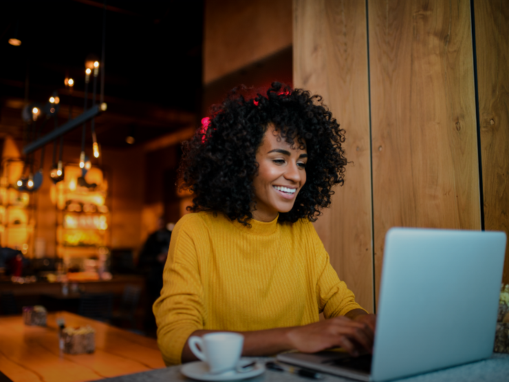 A woman smiling at a laptop screen